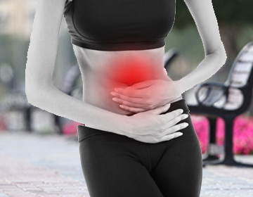 Osoba trzymająca się za brzuch, sygnalizując ból w okolicy jamy brzusznej, z zaznaczeniem czerwonym kolorem miejsca bólu.